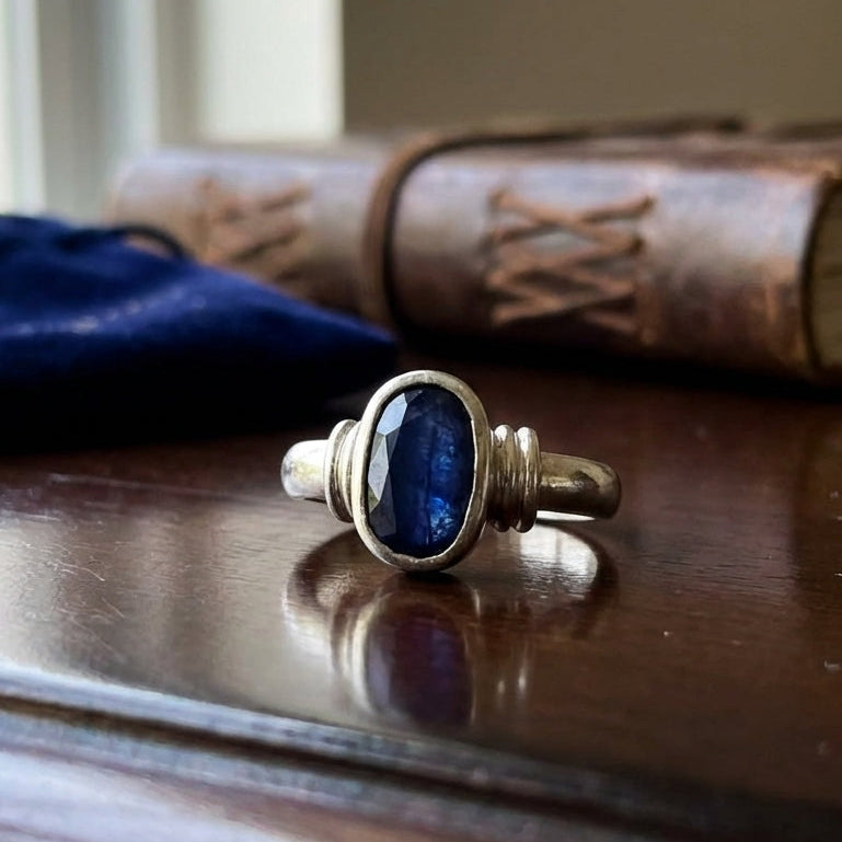 Silver ring with a blue neelam natural stone on a wooden surface with a book in the background