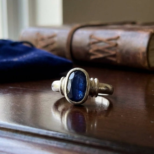 Silver ring with a blue neelam natural stone on a wooden surface with a book in the background
