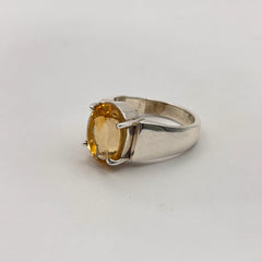 Silver ring with a yellow citrine gemstone on a light gray background
