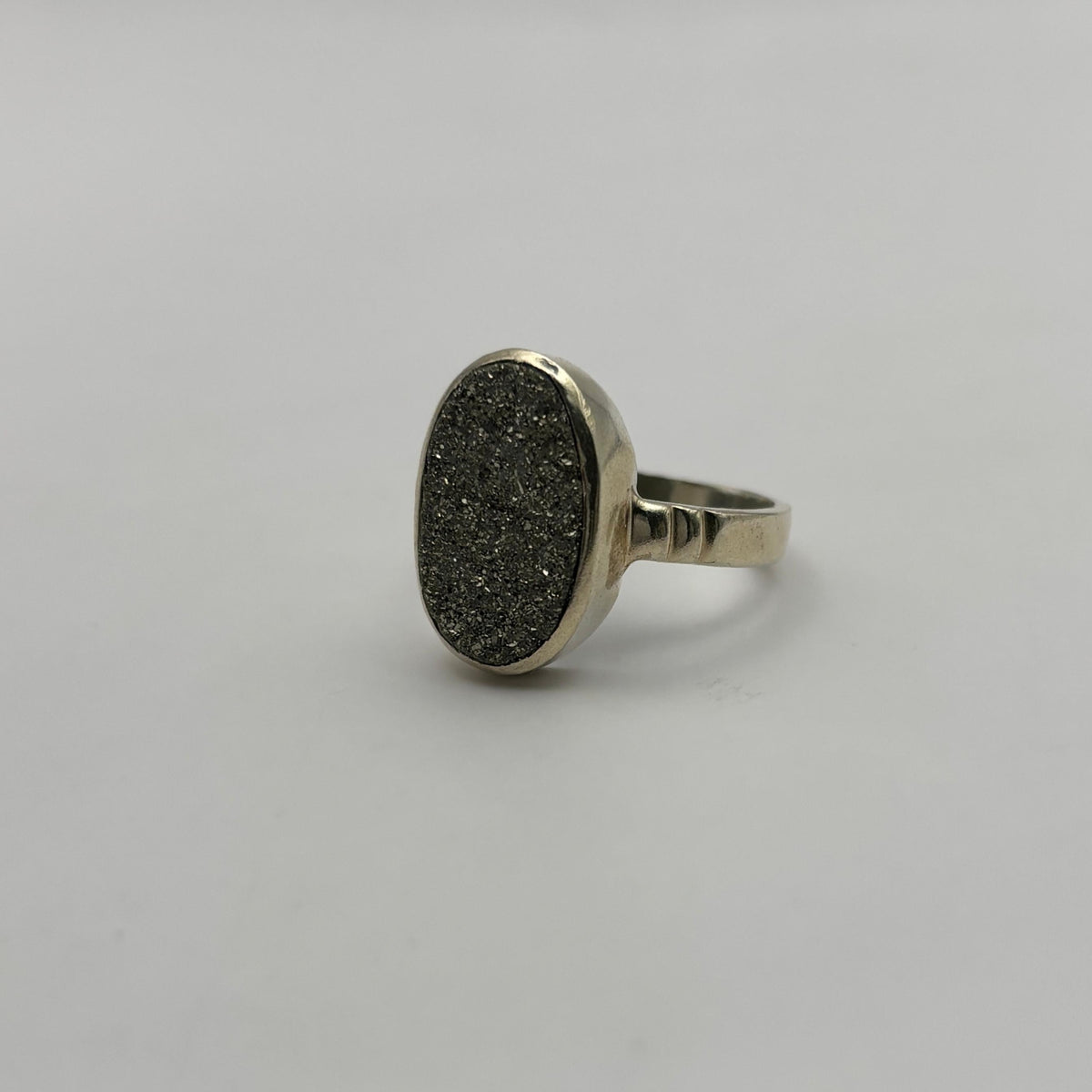Silver ring with a textured oval Pyrite stone on a light gray background