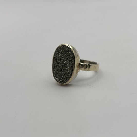 Silver ring with a textured oval Pyrite stone on a light gray background