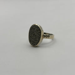 Silver ring with a textured oval Pyrite stone on a light gray background