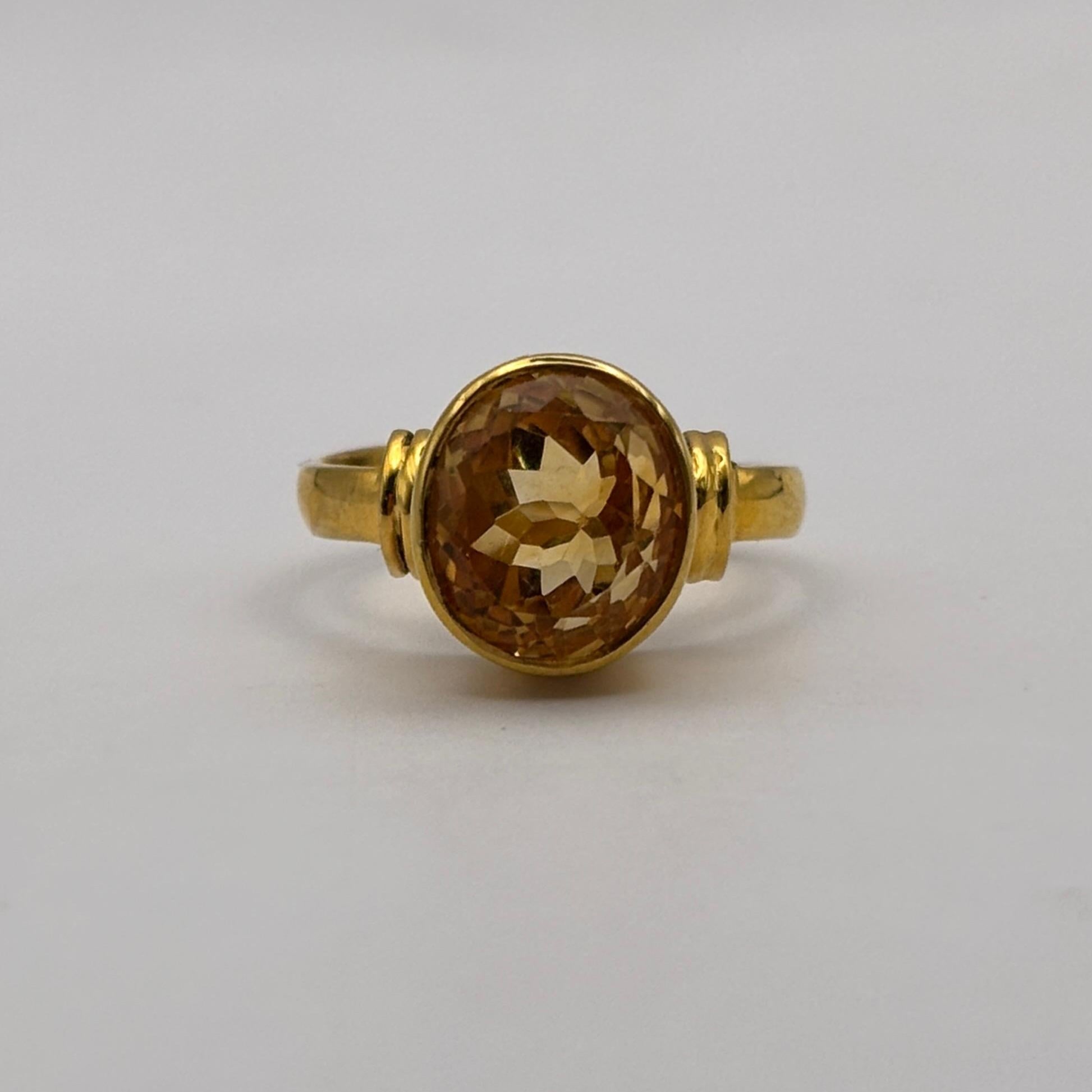 Gold ring with a citrine gemstone on a light gray background