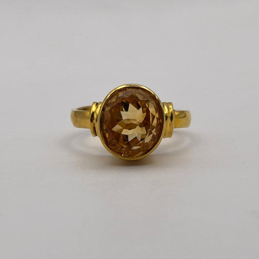 Gold ring with a citrine gemstone on a light gray background