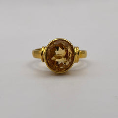 Gold ring with a citrine gemstone on a light gray background