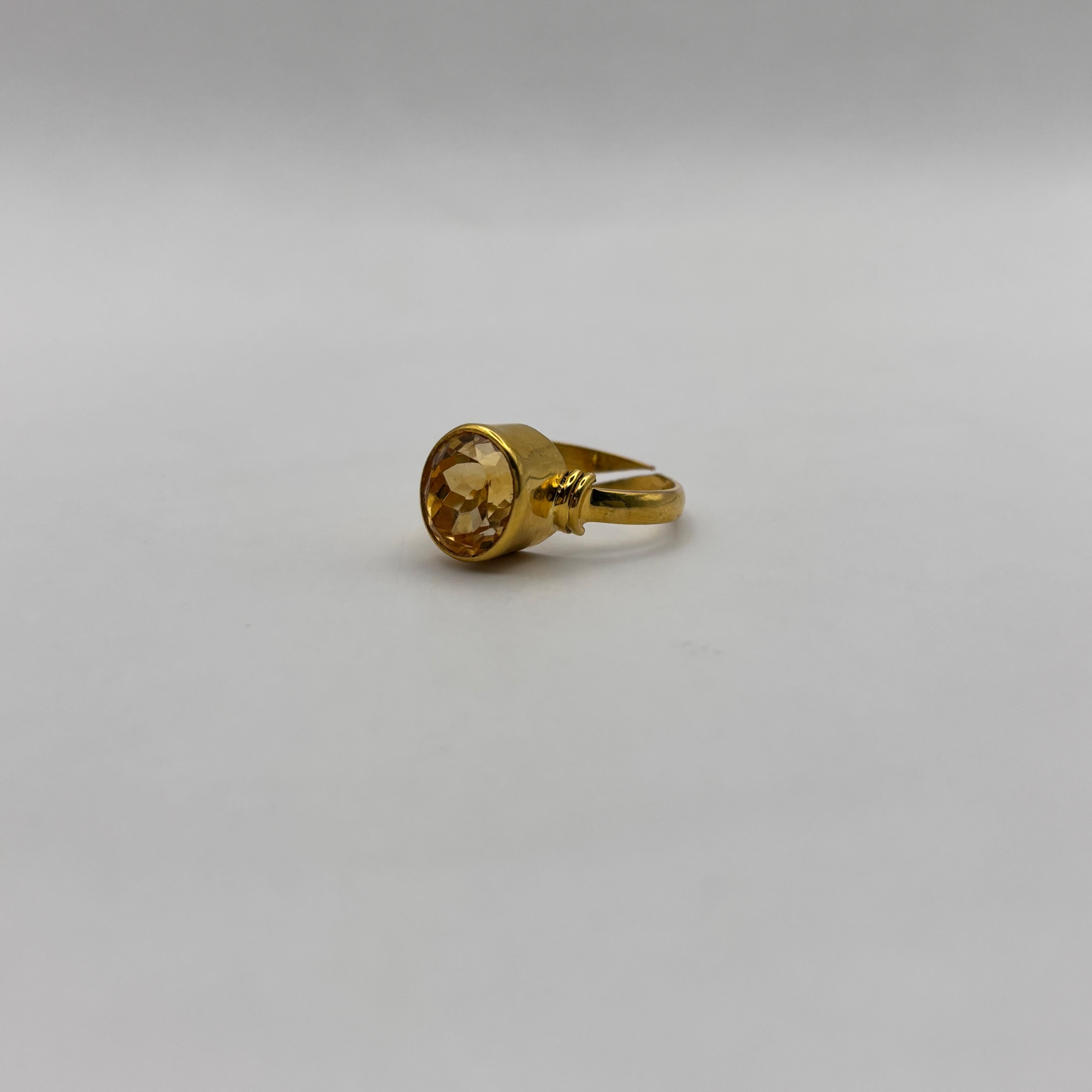 Gold ring with a citrine gemstone on a light gray background
