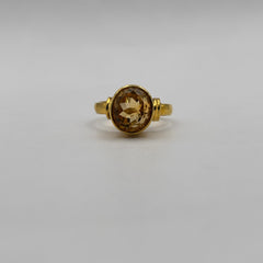 Gold ring with a citrine gemstone on a light gray background