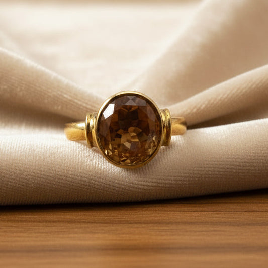Gold ring with a citrine gemstone on a light gray background